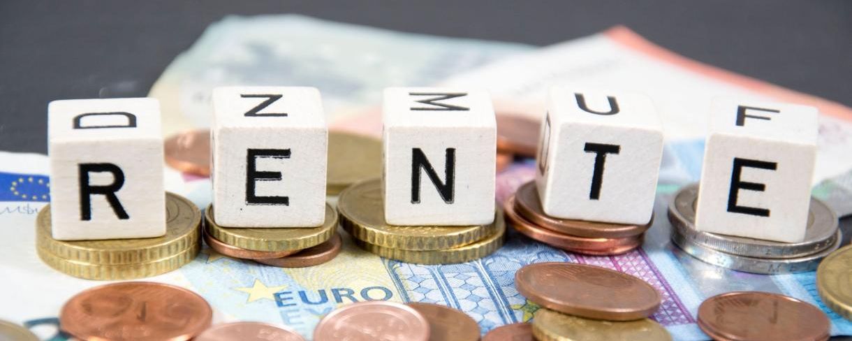 Foto: Würfel mit dem Wort „Rente“ auf Münzen und Geldscheinen.