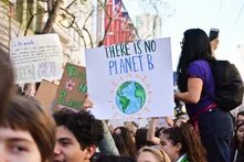 Junge Menschen beim Klimaprotest, eine Person hält ein Schild mit der Aufschrift "There is no planet b" hoch.