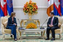 USAID-Administratorin Samantha Power und der kambodschanische Premierminister Hun Manet sitzen auf goldenen Sesseln. Im Hintergrund sind vielen Flaggen.