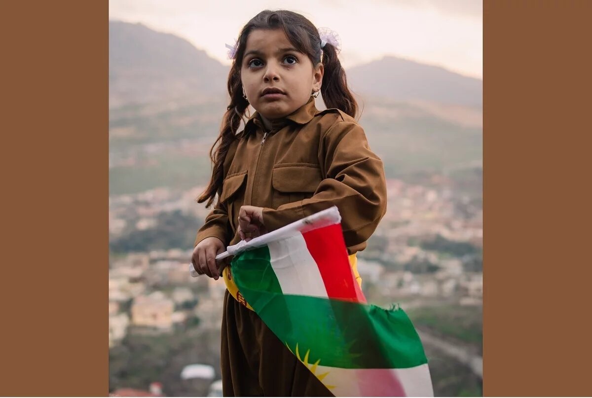 Kind mit kurdischer Flagge in traditionell kurdischer Kleidung