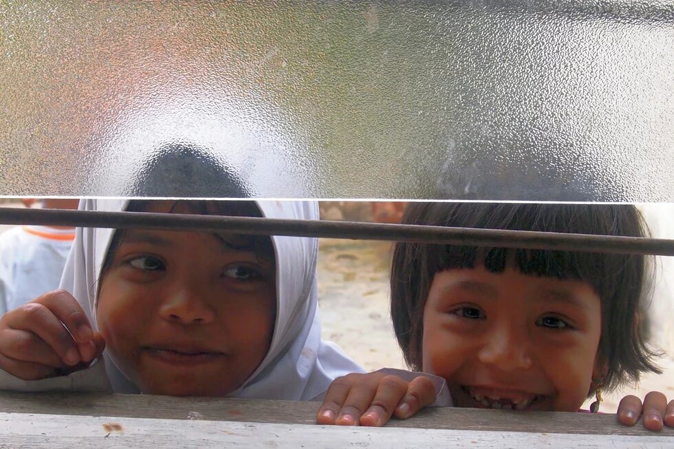 Geflüchtete Kinder in Malaysia Zwei Kinder schauen aus einem Fenster